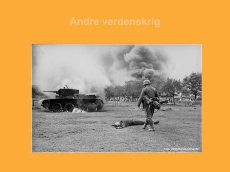 Andre verdenskrig Foto: Tysk soldat inspiserer en død sovjetisk soldat. En sovjetisk stridsvogn står i flammer. Foto: Deutsches Bundesarchiv.